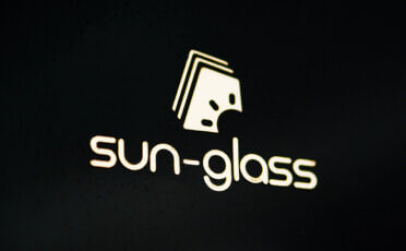 emblemat chromowany na czarnym tle ze złotym logiem i napisem sun-glass
