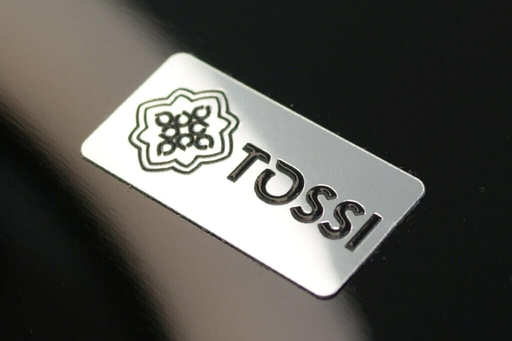 prostokątna firmowa srebrna plakietka logo na produkty marki TOSSI